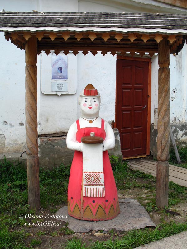 Holzfigur vor dem Eingang des Zentrums „Bereginja“ – Kargopoler Frau mit Brot und Salz, so empfängt man traditionell die Gäste in Russland. © Oksana Fedotova 